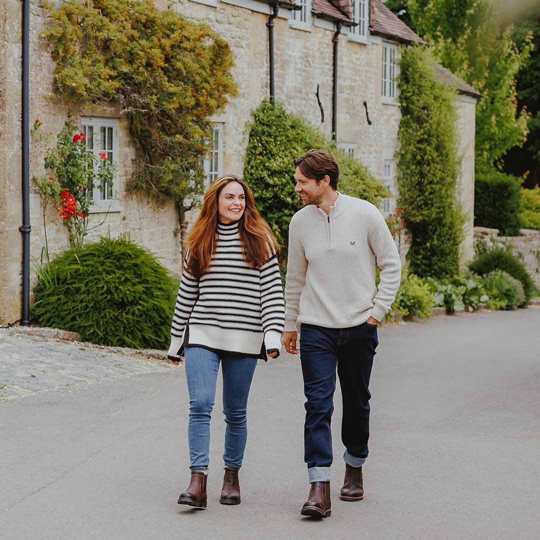 Man and woman walking through a Cotswold village, wearing Cotswold boots