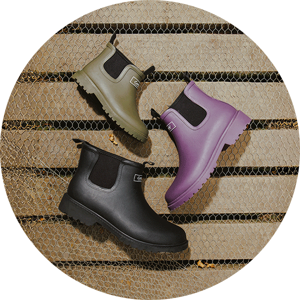 Cotswold Barton wellingtons in three colours laid down on wooden decking and wire mesh.