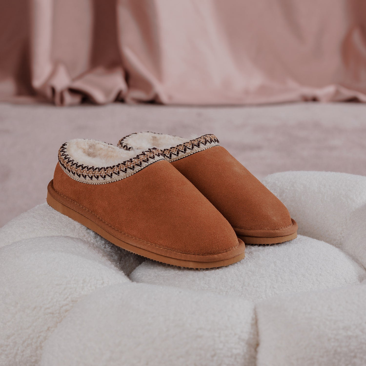 A pair of tan Cotswold Foxmoor Slippers on a white cushion
